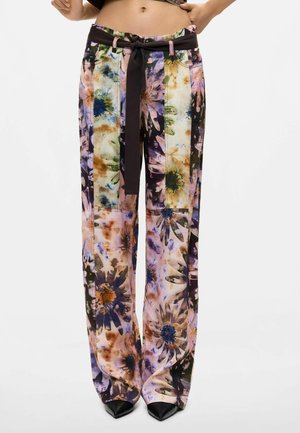 Pantaloni a vita alta con gamba larga, stampa floreale multicolore e cintura in tessuto nero annodata in vita, indossati con scarpe nere a punta.