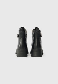 Μαύρες δερμάτινες μποτάκια μέχρι τον αστράγαλο με γερή γόβα, διαθέτουν λουρί και λεπτομέρεια με αγκράφα. Λειασμένο φινίρισμα και σχεδίαση με στρογγυλή μύτη.