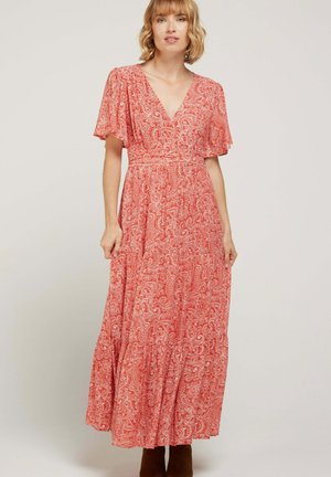 Robe maxi rouge avec un motif paisley blanc, manches courtes volantées, décolleté en V et jupe à volants. Le tissu est léger avec une texture douce.