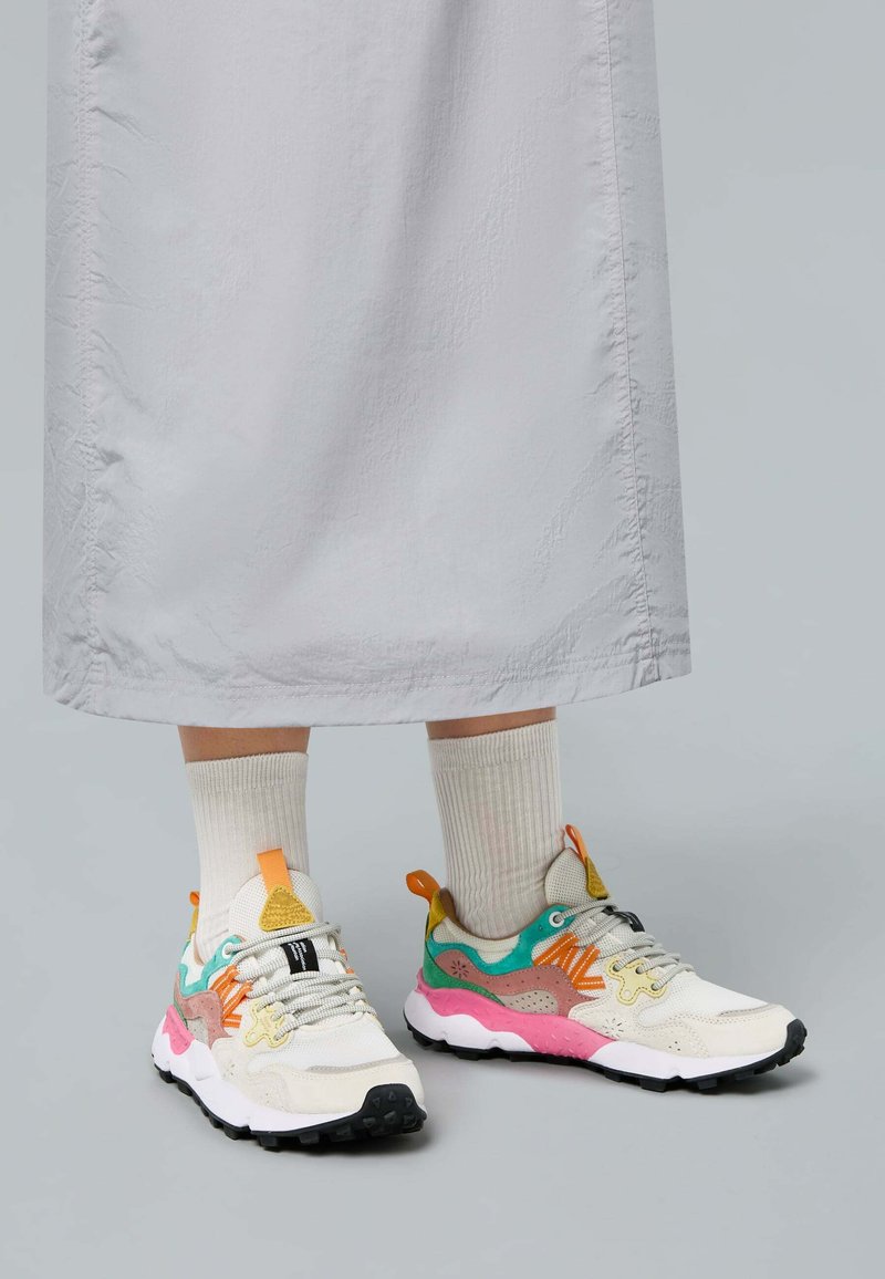 Le sneakers presentano una parte superiore color crema con accenti colorati in turchese, rosa e arancione, pannelli testurizzati e una suola in gomma nera.