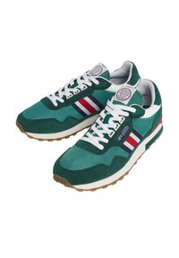 Grüne Wildleder- und Textilsneaker mit weißen Schnürsenkeln, blauen, roten und weißen Streifen an der Seite sowie einer Gummisohle. Auf der Zunge befindet sich ein kreisförmiges Logo.
