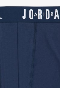 Mørkeblå boxer shorts lavet af blødt bomuldsmateriale, med en bred elastisk talje med "JORDAN" trykt i hvid. Synlige sømdetaljer.