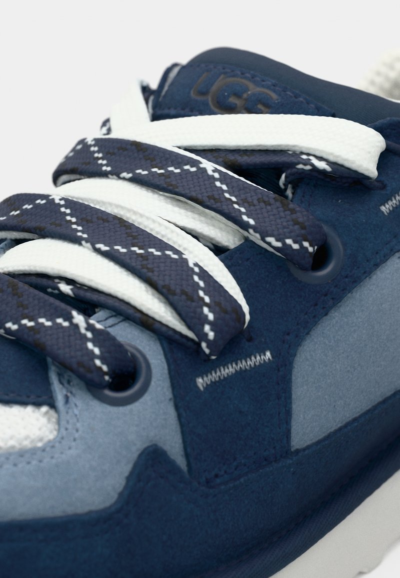 Zapatillas de ante en azul marino y azul claro con malla blanca, cordones redondos que presentan un patrón de diamante y un cuello acolchado. Marca en la lengüeta.