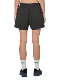 Person iført sorte atletikshorts, hvide crew-sokker med tekst og mørke løbesko, set bagfra mod en hvid baggrund.