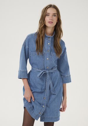 Denim shirt dress featuring a button-up front, mandarin collar, 3/4 sleeves, waist tie, and front pockets. Light blue color with a soft texture.