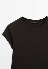 T-shirt marron foncé à manches courtes avec col rond, coutures raglan et étiquette Massimo Dutti visible au niveau du col.