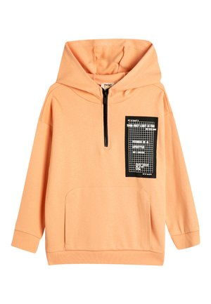 Sudadera de color durazno hecha de tela suave, con un cierre de media cremallera en el frente, un bolsillo frontal y un parche de diseño gráfico negro en el pecho.
