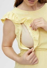 Abito giallo con maniche a volant, con un'apertura laterale che rivela un sottolotto beige. Tessuto morbido con un design rilassato.