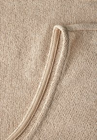Tessuto lavorato a maglia beige con una superficie textured; presenta un collo rotondo e un bordo liscio e contrastante lungo il bordo.
