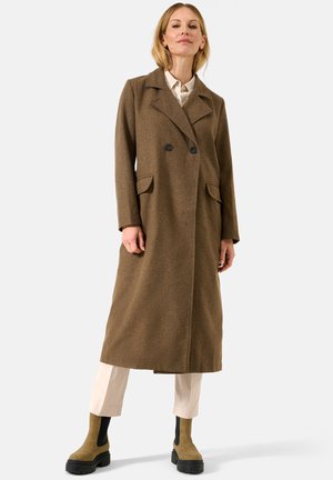 Brown wool long coat with a double-breasted design, notched lapels, and side pockets, paired with beige trousers and beige and black ankle boots.