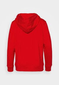 Sudadera con capucha roja y mangas largas, fabricada con tela suave. Cuenta con un bolsillo tipo canguro y puños acanalados. Diseño liso, sin patrones ni adornos.
