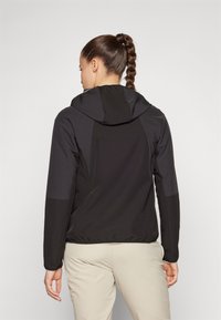 Veste légère noire avec capuche, dotée d'une texture lisse, d'un contraste de panneaux et de poignets élastiques. Conçue pour un silhouette ajustée.
