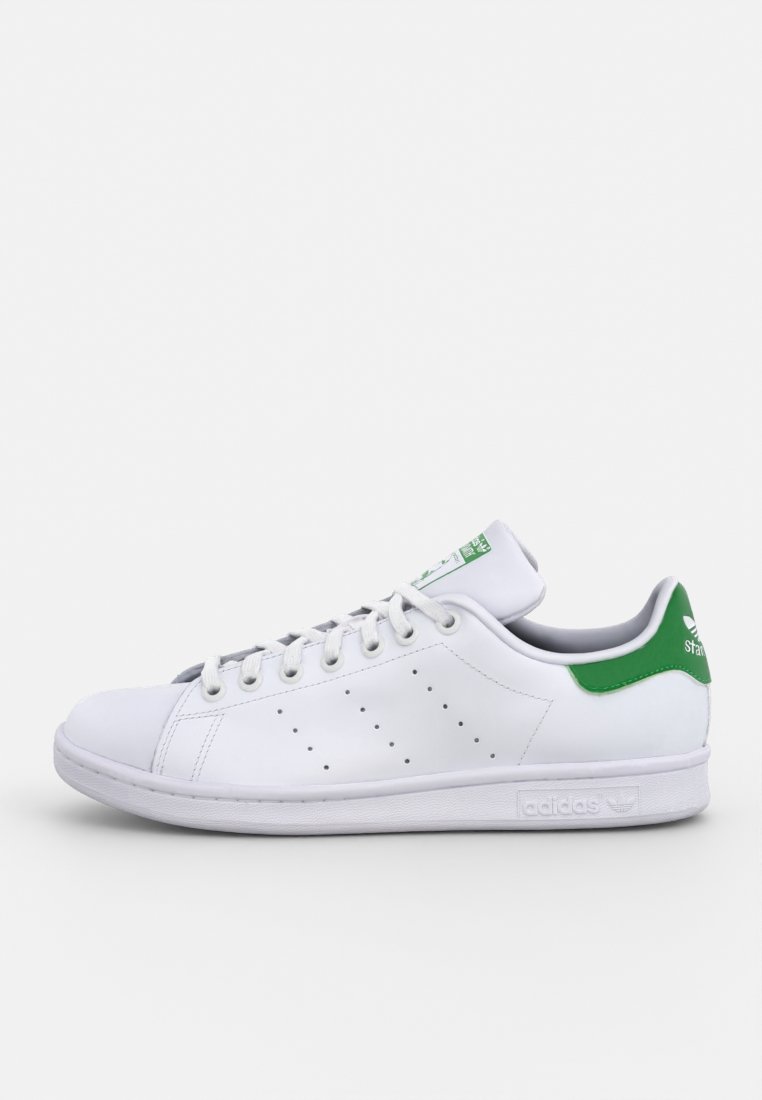 Baskets en cuir blanc avec des accents verts, dotées de lacets, de détails perforés sur les côtés et d'un design à bout arrondi. Logo au niveau du talon.