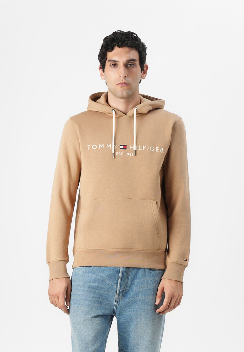 Béžová mikina s kapucňou, šnúrkami, prednou vreckom a bielym logom "TOMMY HILFIGER". Mäkká tkanina, neformálny dizajn, dlhé rukávy a rebrované manžety.