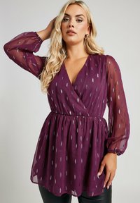 Blusa viola trasparente a scollatura a V con maniche lunghe, vita elastica e motivo a pois argentati. Tessuto morbido con una vestibilità comoda.