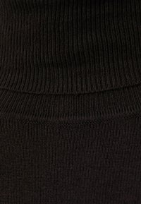 Svart ribbat stickat tyg med en tät textur, featuring en hög krage och sömlösa kanter, lämpligt för kläder.