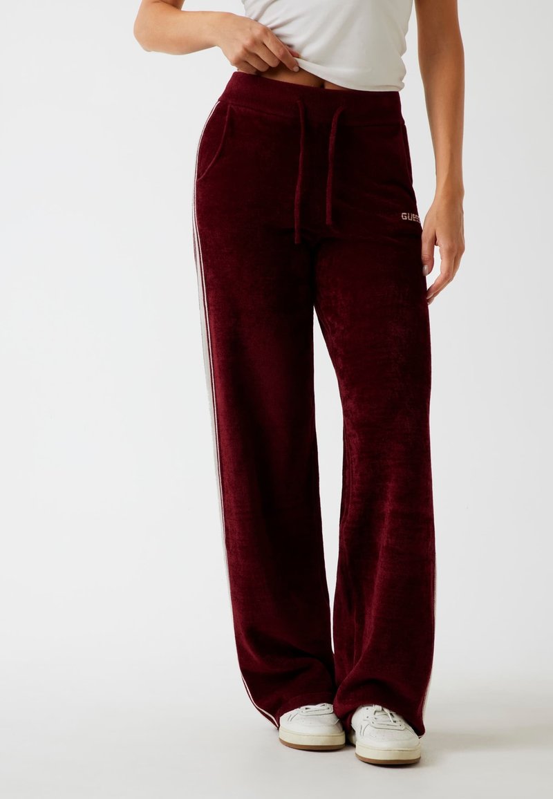 Burgunderfarbene Velours-Sweatpants mit entspannter Passform, seitlichen Streifen, elastischem Bund, Kordelzug und Fronttaschen. Mit Logoakzenten.