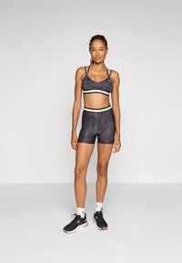 Black athletic crop top and shorts set with a subtle pattern, featuring white striped accents, paired with black sneakers and white socks.