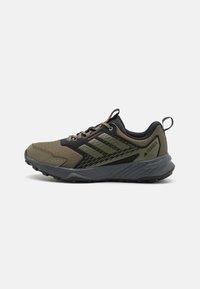 Groene en zwarte sport schoenen met een gestructureerde bovenkant, platte veters en een duurzame rubberen zool met grip patronen.