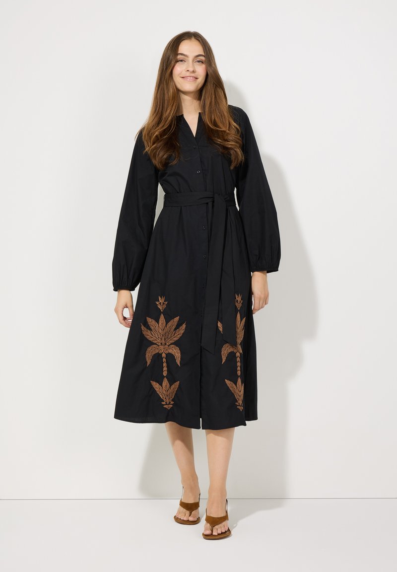Schwarzes Hemdblusenkleid mit langen Ärmeln, versehen mit brauner Blumenstickerei und einem passenden Gürtel in der Taille. Aus leichtem Stoff gefertigt.