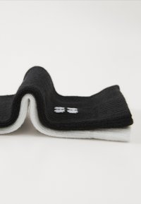 Calcetines en blanco y negro con textura acanalada. La sección negra presenta costuras blancas, creando una apariencia estratificada.