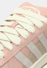 Ροζ σουέντ αθλητικό παπούτσι με κρεμ κορδόνια, υφασμάτινη μπεζ λεπτομέρεια και λευκό λογότυπο στη γλώσσα. Λαστιχένια σόλα με ραφή ζιγκ-ζακ.