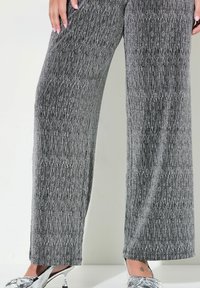 Wijdvallende broek in een metallic zilver en zwart verticaal streep patroon, met een zachte textuur en een middelhoge tailleband. Zilveren hakken.