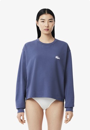 Purple cotton sweatshirt with long sleeves, a crew neck, and a small white logo on the chest. Designed for a relaxed fit.