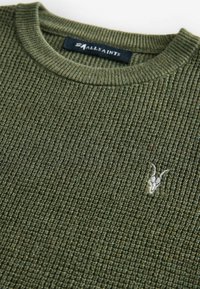 Maglione oversize verde oliva in maglia con una trama a coste, caratterizzato da un collo rotondo e un piccolo logo ricamato sul davanti.