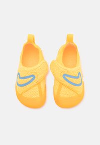 Gelbe Slippers mit einem strukturierten Strickobermaterial, orangefarbener Gummisohle und blauen Nike-Swoosh-Details. Mit Zuglaschen für ein einfaches An- und Ausziehen.