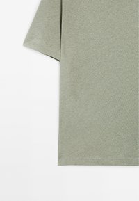 Světlý zelený tričko s krátkým rukávem, vyrobené z měkké látky. Má jednoduchý, nezdobený design a hladkou strukturu.