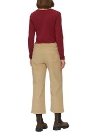 Beige corduroy wijde broek met achterzakken, gecombineerd met een lange mouw bordeaux top en bruine enkellaarzen. Gladde textuur zichtbaar.