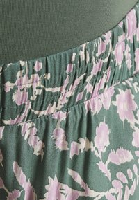 Floral skirt: green fabric with purple and white floral pattern, elastic waistband, soft texture, and relaxed fit design.