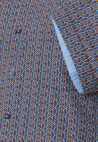 Overhemd met knopen, voorzien van een geometrisch patroon in rood, blauw, oranje en wit, met een blauwe binnenplacket en een enkele knoopsluiting.