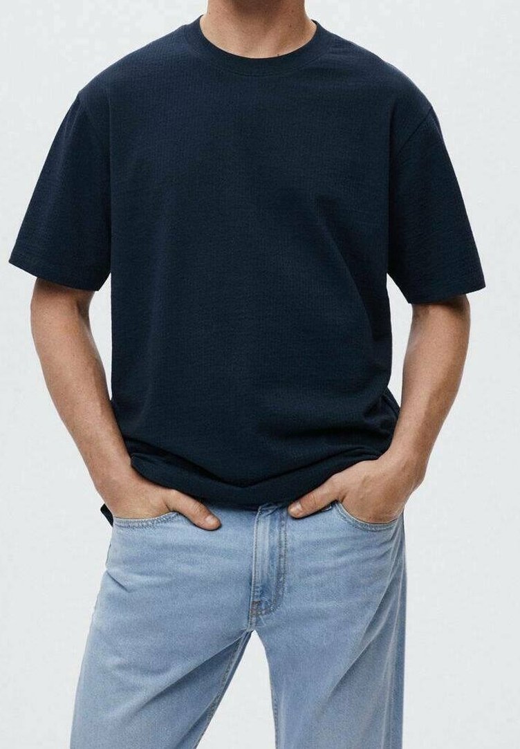 T-shirt bleu marine à manches courtes avec un motif texturé, coupe décontractée, col ras du cou, associé à un jean droit bleu clair.