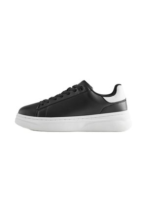 Baskets basses noires avec talon blanc et semelle blanche épaisse, avec des lacets noirs et une tige en cuir lisse.