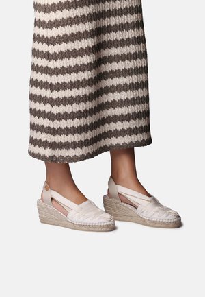 Espadrilles compensées avec tige en tissu tressé beige clair et semelle en jute naturel, présentant un design à lanières croisées et un talon ouvert.