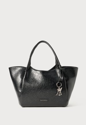 Black faux leather tote bag with a glossy finish, tapered sides, dual handles, and a silver keychain accent. Features a logo plaque on the front.