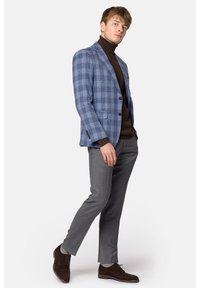 Niebieska i szara marynarka w kratę, brązowy sweter z golfem, szare spodnie, ciemnobrązowe buty. Marynarka ma guziki i slim fit.