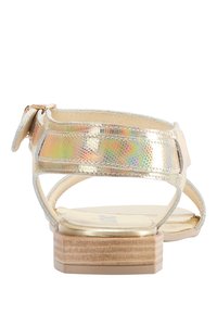 Metallic guld sandal med en klodset hæl, der har en struktureret rem og en bageste spænde. Inkluderer en glat, beige fodbæd.