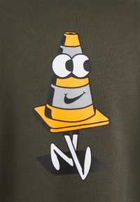 Kreslený design černé a oranžové dopravní kuželky na olivově zelené látce. Obsahuje velké oči a úsměv, s bílými akcenty na základně.