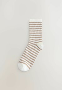 Enkele beige en witte gestreepte sok met een witte teen en hiel, plat gelegd op een effen lichte achtergrond.