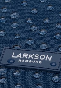 Tengerészkék szövet vízcseppekkel; texturált felülettel rendelkezik, és egy fehér logó címke található rajta, amelyen az áll: "LARKSON HAMBURG."