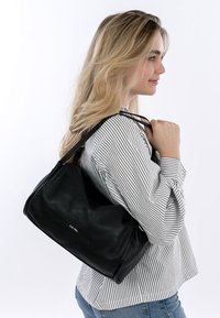 Schwarze Lederhandtasche mit strukturierter Oberfläche, lässigem Design und dünnen Schulterriemen. Verfügt über ein dezentes Markenlogo auf der Vorderseite.