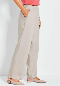 Lichtbeige, wijde broek met een elastische tailleband en zijzakken. De stof heeft een soepele textuur, ideaal voor casual gebruik.