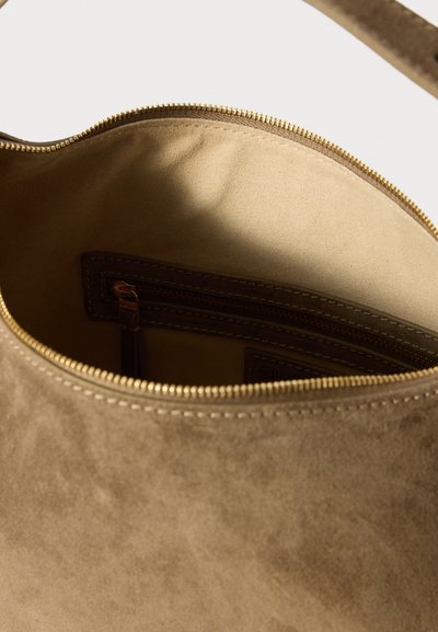 Brown suede bag interior with a smooth texture, featuring a zipper closure and a separate zippered pocket, highlighting craftsmanship details.