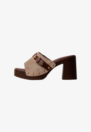 Mule beige en daim à bout ouvert avec talon plateforme en bois marron, clous dorés sur le côté et bride ajustable en cuir marron avec boucle dorée.