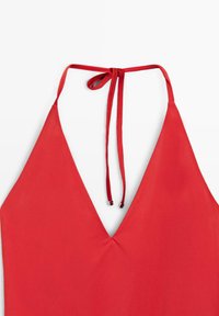 Haut dos-nu rouge avec des bonnets triangulaires et de fines attaches qui se nouent autour du cou, avec des embouts métalliques aux extrémités des liens.