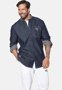 Dunkelblaue Jeanshemd mit Knopfschluss, kontrastierenden Manschetten und einer Brusttasche. Verfügt über ein dekoratives Design auf der Tasche und dem Saum.