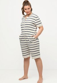 Stribet jumpsuit i creme og marineblå med korte ærmer, lynlås foran, elastisk talje og sidelommer. Uformelt design med en afslappet pasform.